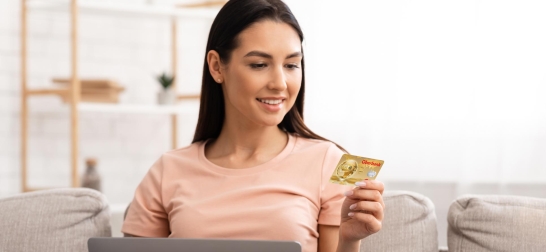 Lächelnde Frau schaut auf ihre Oberbank Debitkarte