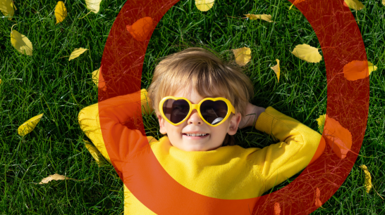 Junge mit Sonnenbrille liegt in grüner Wiese