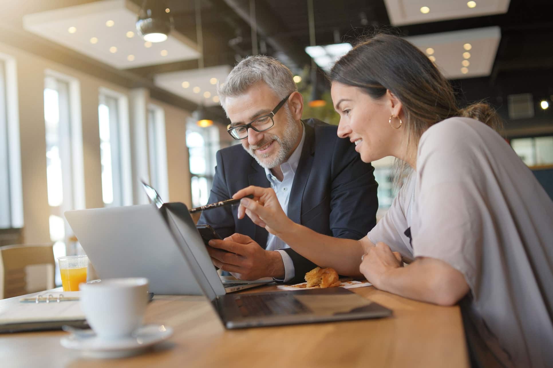 Mann und Frau sitzen an Laptop und unterhalten sich