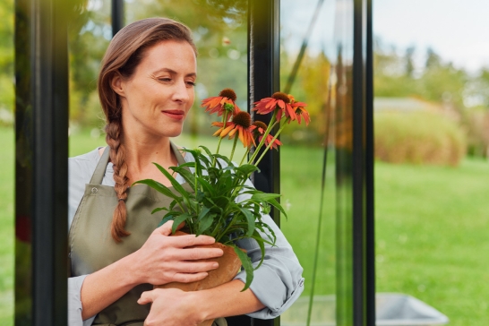 Eine Frau hält einen Blumentopf mit roten Blumen