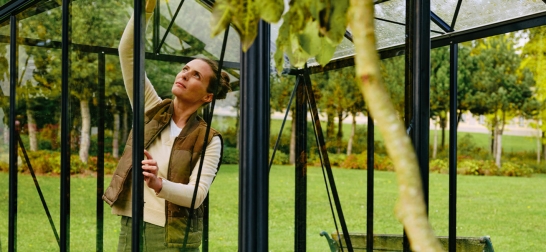 Eine Frau baut ein Glashaus zusammen