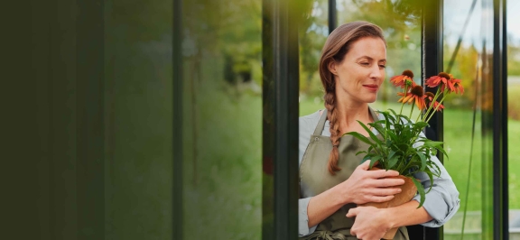 Eine Frau hält einen Blumentopf mit roten Blumen