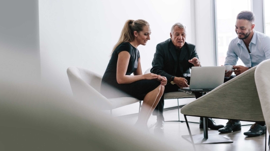 3 Personen sitzen bei einem Meeting
