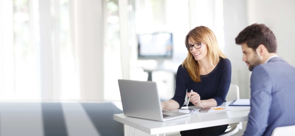 Mann und Frau sitzen vor Laptop