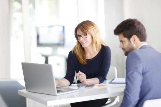 Mann und Frau sitzen vor Laptop