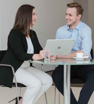 Frau und Mann schauen in einen Laptop