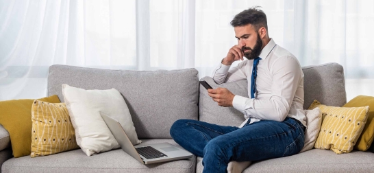 Mann auf Couch liest den Oberbank Newsletter am Handy