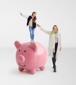 Kind steht auf rosa Sparschwein. Daneben steht eine Frau und hält ihre Hand.