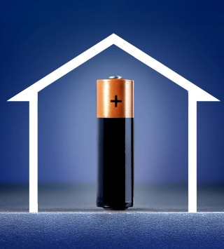 Jetzt Wohnen Artikel: Stromspeicher für zu Hause - blauer Hintergrund mit weiße Umrandung eines Hauses, mit Batterie innerhalb des Hauses