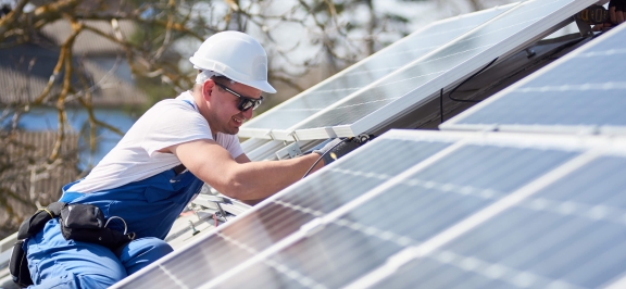 Mann arbeitet an Photovoltaik-Anlage am Dach